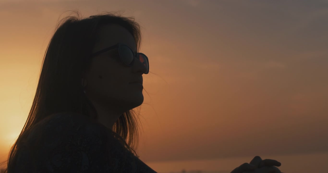 Woman leans on the stone wall at sunset