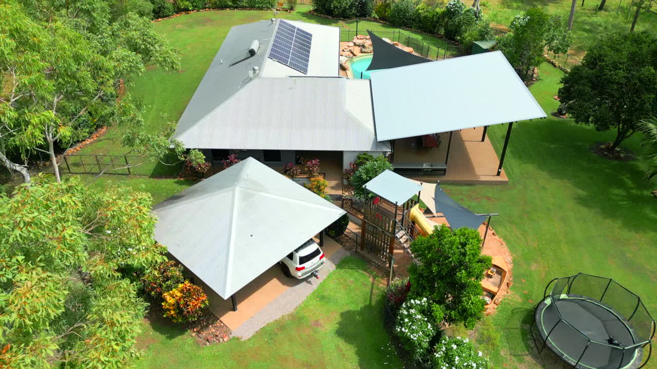 dron aéreo de lujo elegante casa tropical con coche tirando en carport garaje de lado abierto, seguimiento de ojo de pájaro