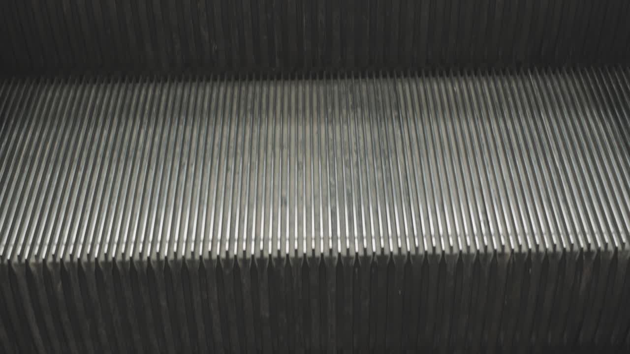 반복되는 패턴으로 내려가는 금속 에스컬레이터의 클로즈업 4k 비디오는 시내 생활의 상징적인 모습을 보여줍니다.