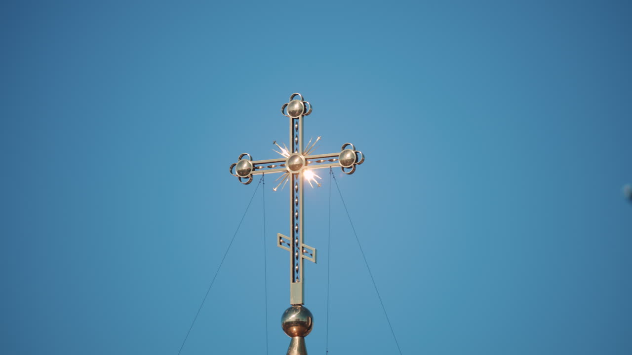 Elegant metallic church cross glowing under clear blue sky