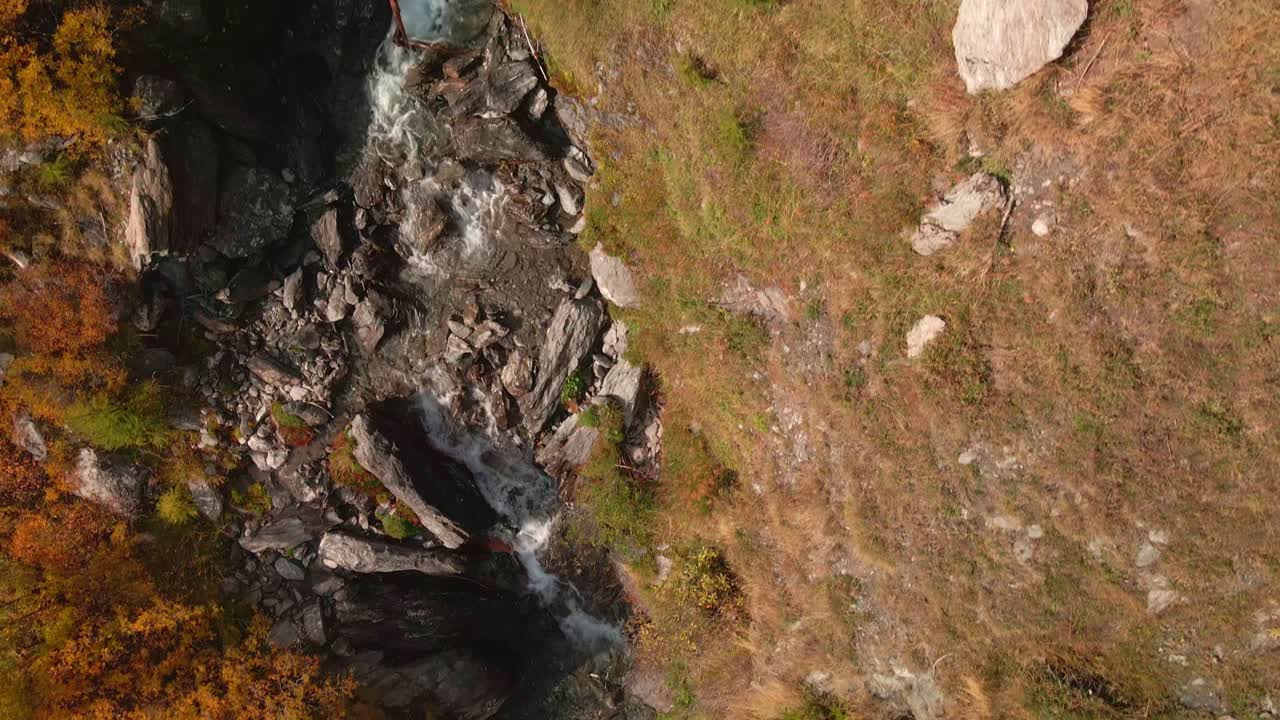 riachuelo de agua dulce sobrevolando el valle rocoso con bosque otoñal en piemonte, italia