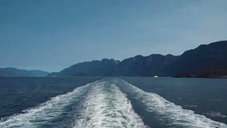 Slow-Motion-View-of-the-Wake-Behind-a-Ferry-With-Shoreline-In-Distance