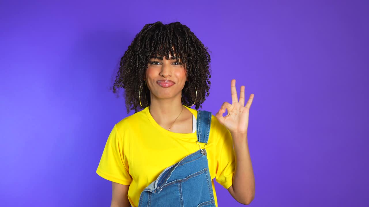 Woman with Curly Hair and Yellow Shirt Showing OK Sign