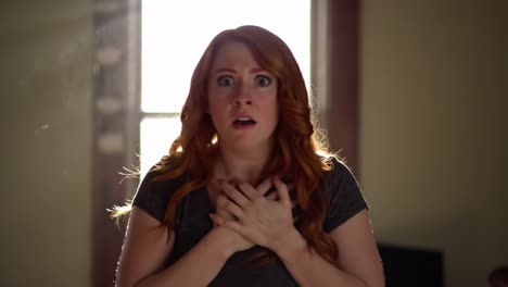 a woman experiences intense fear as she clutches her chest, her surprised expression illuminated by sunlight streaming through a window behind her. the atmosphere is charged with suspense.