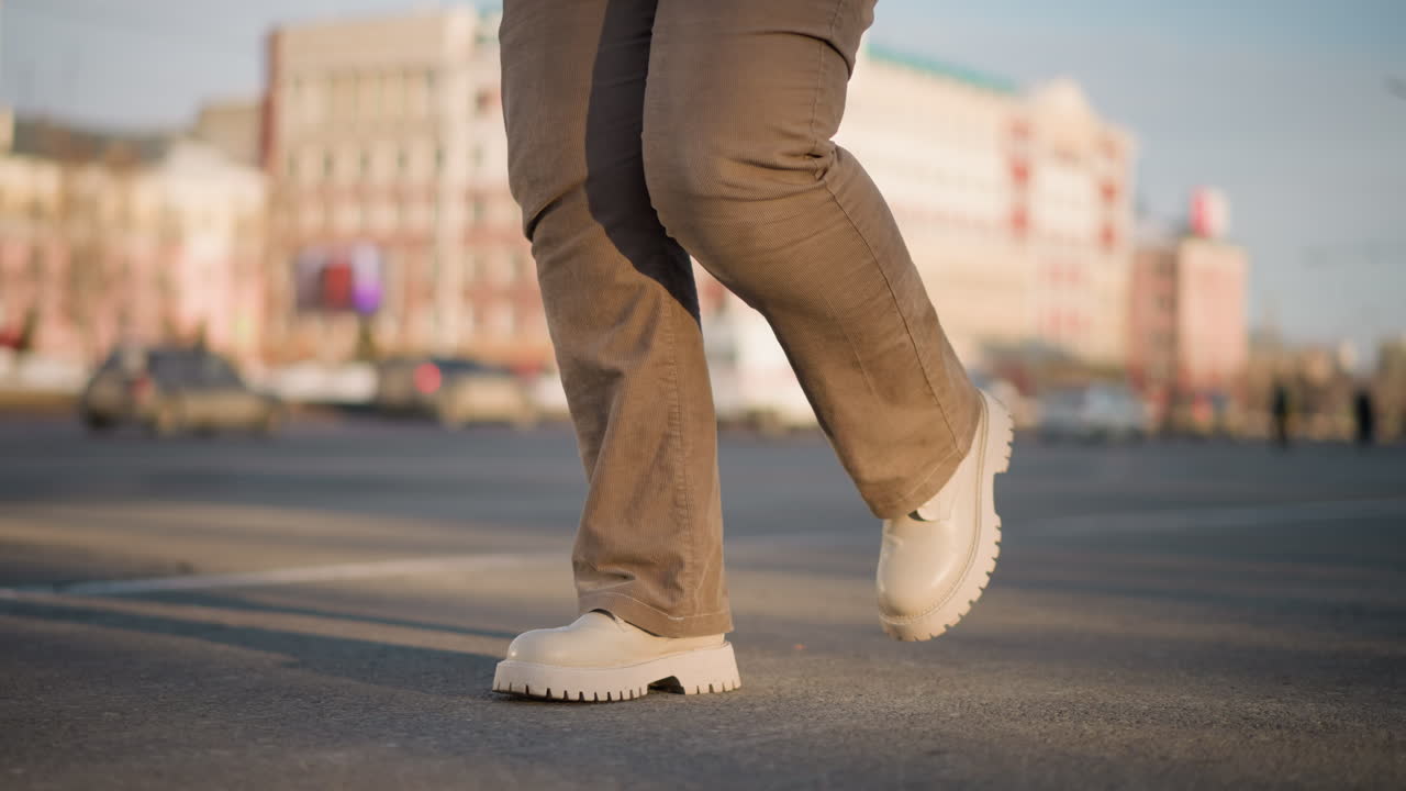 Leg view of youth dancing rhythmically on wet tiled pavement with melting snow edges, scattering water droplets through precise steps, reflecting urban winter mood under soft morning sunlight