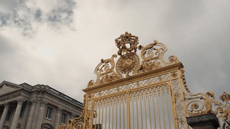 the golden main gate of honour with ornaments and crown of castle versailles in paris france on a cloudy day