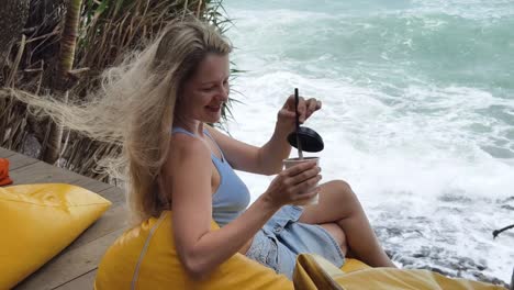 una mujer disfrutando de una copa junto al océano.