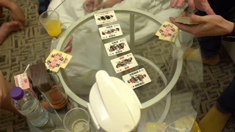 grupo de jóvenes jugando a las cartas en una mesa de cristal en hong kong