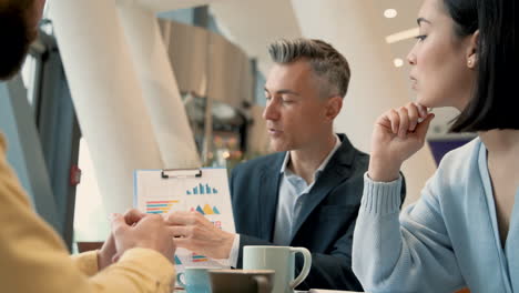 a work team discusses details of some data in a report at a coffee shop 1