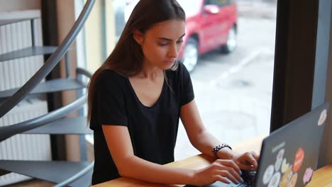 Junge-Frau-Sitzt-Mit-Ihrem-Laptop-Im-Kaffeehaus-Am-Fenster-Und-überlegt,-Was-Sie-Schreiben-Oder-Wie-Sie-Antworten-Soll.-Dann-Hat-Sie-Es