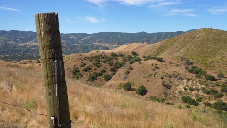 poste de valla panorámica apretado a la izquierda que muestra las colinas de la tierra de ganado