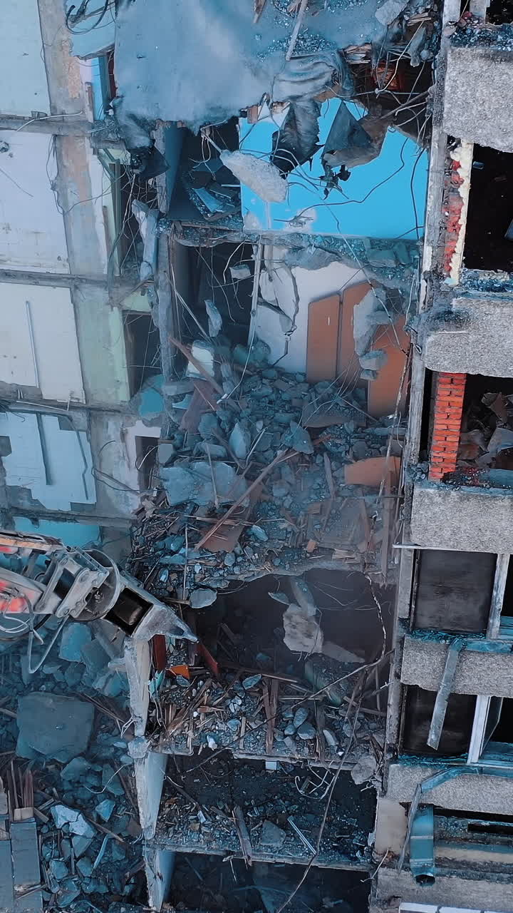 Excavator claw caught the piece of destructed house. Site of the ruins of old building. View from above. Vertical video