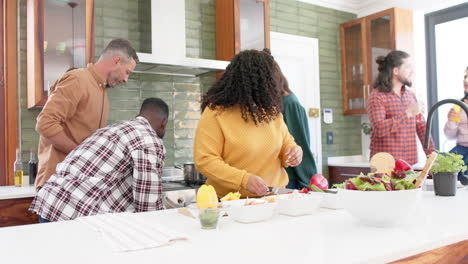 happy diverse male and female friends preparing food together in kitchen