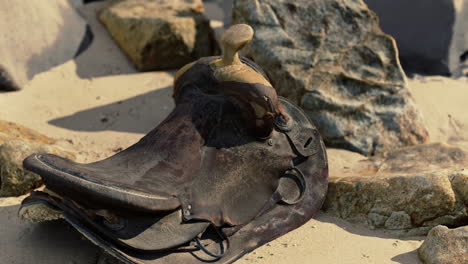 una silla de caballo muy vieja en la playa de arena