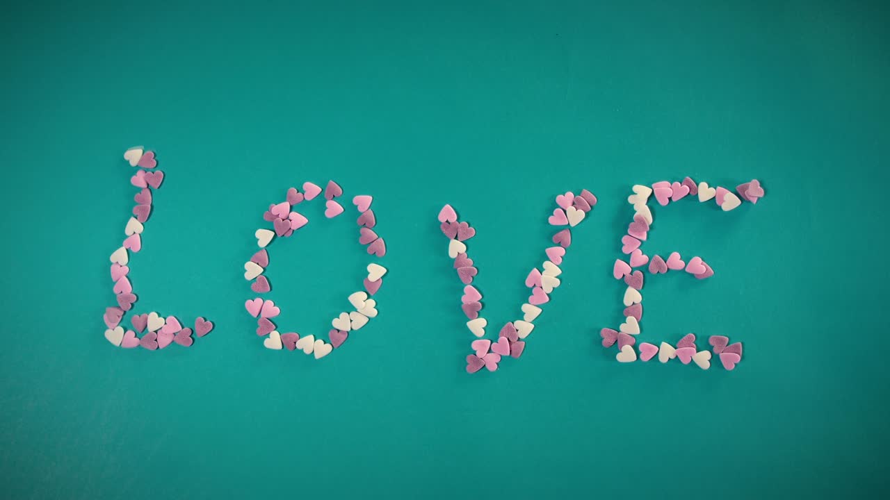 심장 모양의 사탕을 가진 스 모션 애니메이션이 사랑이라는 단어를 만니다.