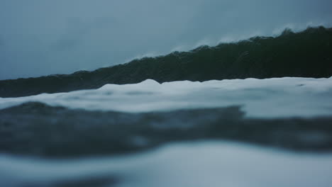 frothing ocean water surface with lip of wave and mist crashing down into ocean