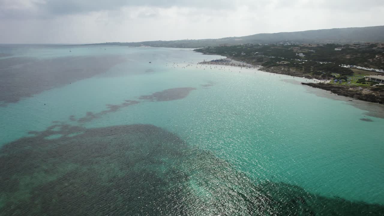 Avvicinamento aereo contro il sole alla spiaggia La Pelosa, uno dei luoghi più belli della Costa Smeralda in Sardegna.