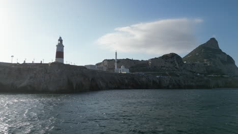 A-low-flying-drone-shot-flying-towards-cliffs-at-the-southernest-point-of-Gibraltar-below-its-red-and-white-lighthouse