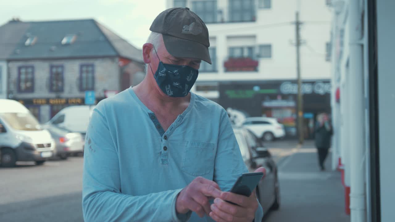 hombre maduro con mascarilla mira el letrero saca el teléfono