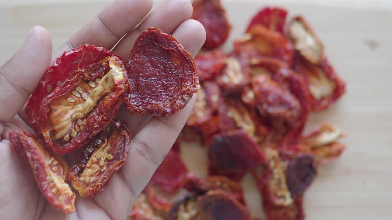 A hand holding sun-dried tomatoes