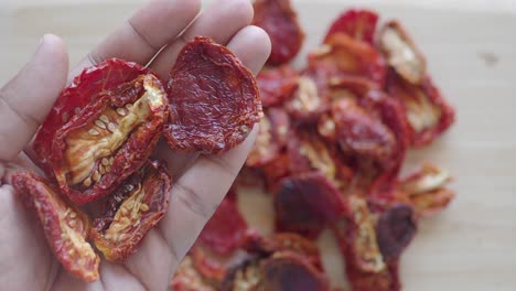 a hand holding sun-dried tomatoes