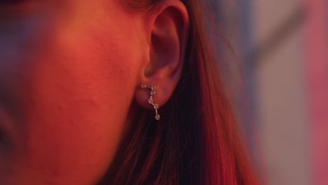 girl ear earring close up, luxury jewelry earpiece, glass diamonds, glittering, shimmering in red light.