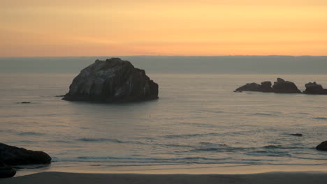 Hermosa-Puesta-De-Sol-Sobre-El-Tranquilo-Océano-Pacífico-En-Bandon-Oregon,-Famosa-Roca-Facial