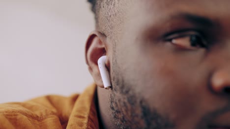 african american man putting wireless earbuds in his ears, enjoying new device