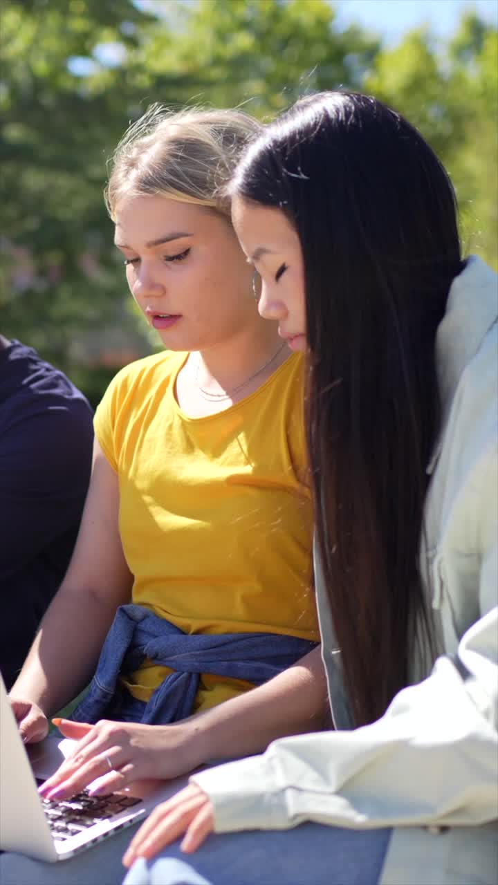Students collaborating on a laptop outdoors