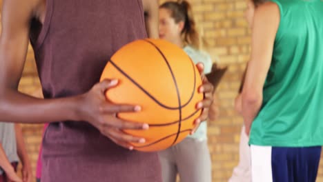 niño de secundaria de pie con el baloncesto en la cancha