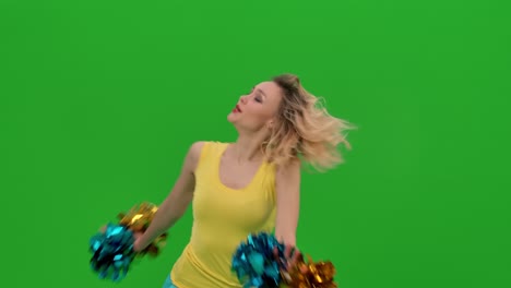 a cheerleader dances a fiery cheerleader dance with pompoms in the studio on a green screen. the girl moves her hips and arms, does a vertical split, whirls, bends in a dance. close up. slow motion