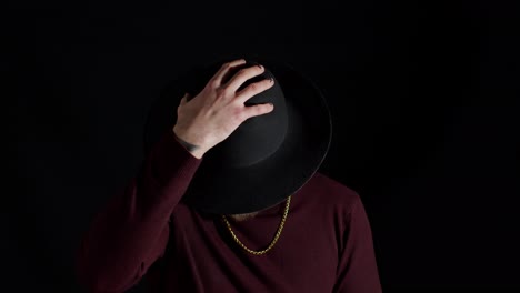 Portrait-of-seductive-smiling-young-man-in-trendy-stylish-clothes-wearing-hat-on-black-background