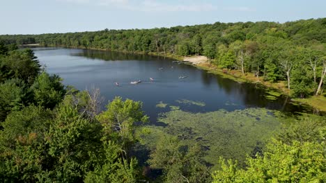 Drone-flyover-summer-trees-to-pond-with-canoes-shot-in-pocono-mountains