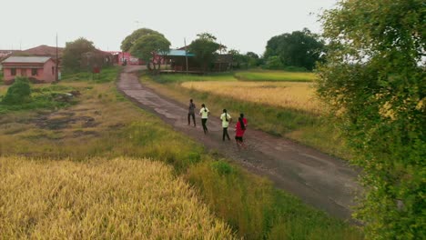 Estudiante-Del-Pueblo-Volviendo-A-Casa-De-La-Escuela-En-Puesta-De-Sol-Niñas-Practicando-Para-Correr-Maratón-Sin-Calzado