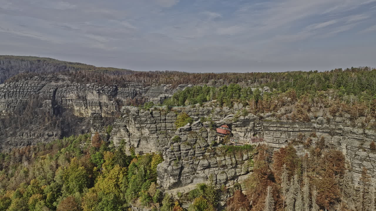 Hrensko Czechia Aerial v2 drone flyover capturing spectacular natural sandstone arch Pravcicka Archway and Falcon's nest Hotel Sokol&iacute; hn&iacute;zdo on the rocky cliff - Shot with Mavic 3 Cine - November 2022