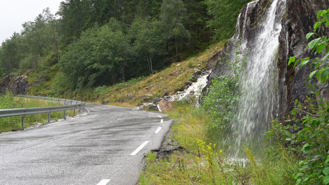 도로 의 언덕에서 많은 물이 내려오고 있습니다. 노르웨이 서부의 시골 도로입니다. 비가 오는 날입니다.