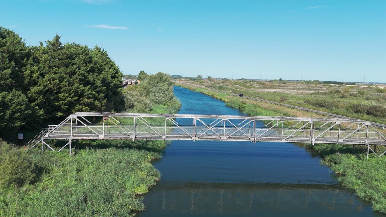 Bridge over calm river with nature, blue sky, and serene landscape