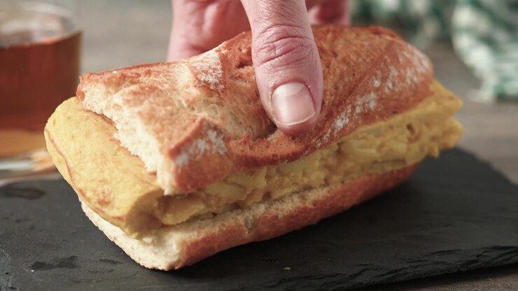 Spanish potato omelette sandwich on wooden table. Bocadillo de tortilla