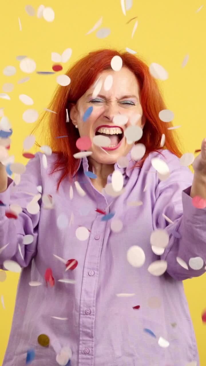 Woman celebrating with falling confetti on a yellow background