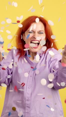 woman celebrating with falling confetti on a yellow background