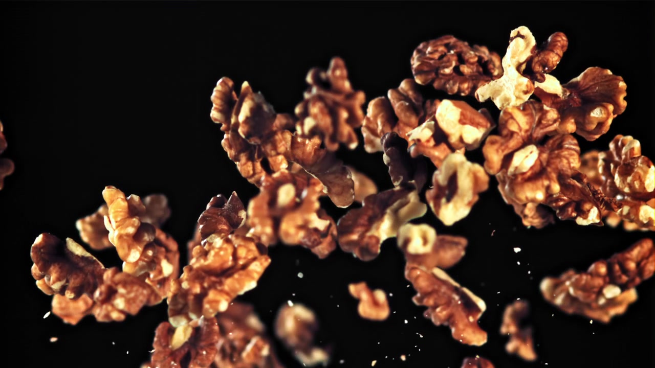 Shelled Walnuts Falling in Slow Motion on Black Background