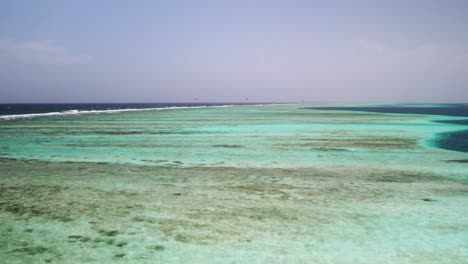 Ein-Atemberaubendes-Korallenriff-In-Klarem,-Türkisfarbenem-Wasser-Unter-Einem-Strahlend-Blauen-Himmel,-Luftaufnahme