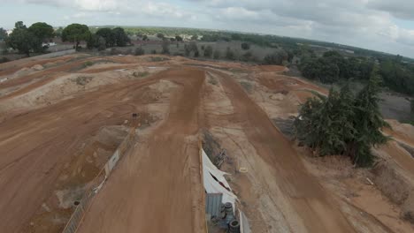 Cámara-Lenta-Fpv-Aérea-Sobre-Pilotos-De-Motocross-En-Pista-De-Tierra,-Día-Nublado