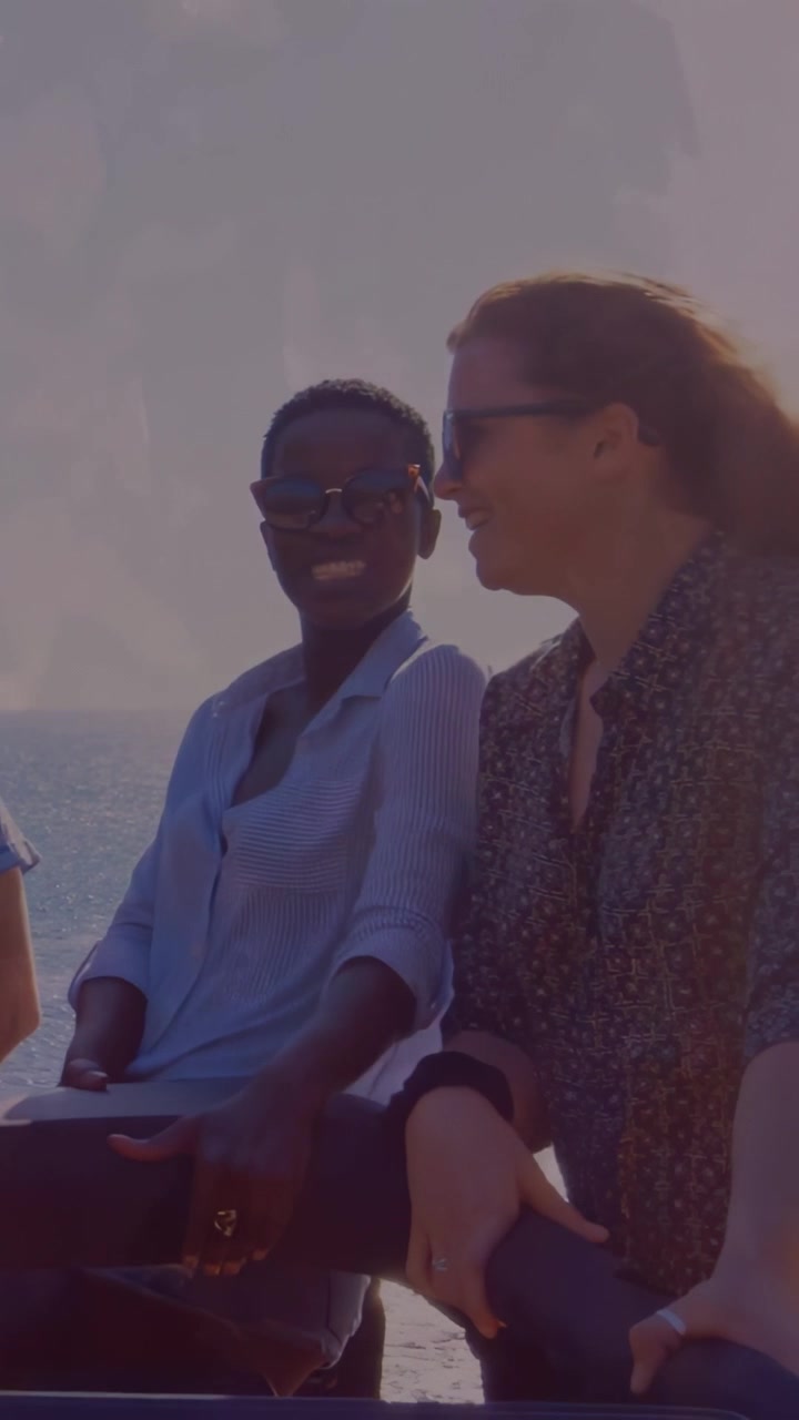 Vertikal video: 3 venner læner sig op ad rækværk ved havet, den til højre bevæger sig og udløser latter, rejse.