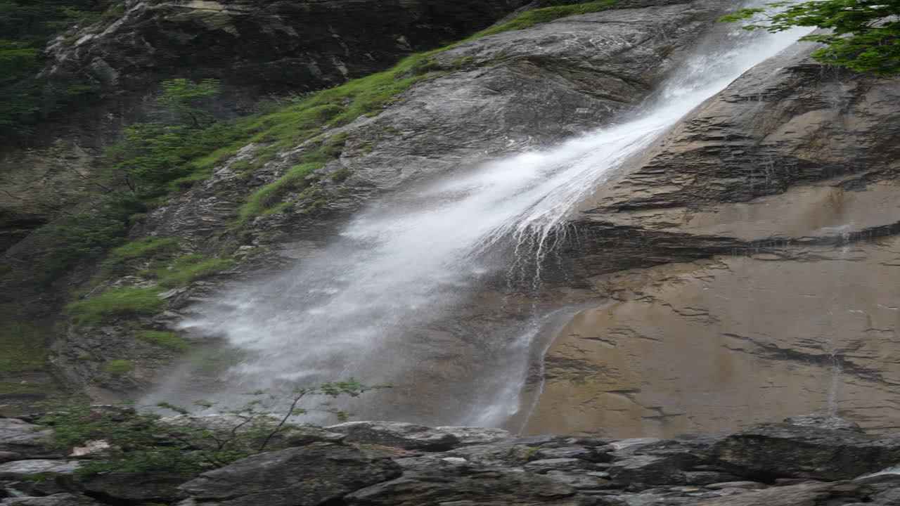 Powerful waterfall crashing down a sheer rock cliff face near Klöntalersee, Klöntal, Glarus, Switzerland. Captures nature's raw force, pristine beauty, and refreshing alpine environment