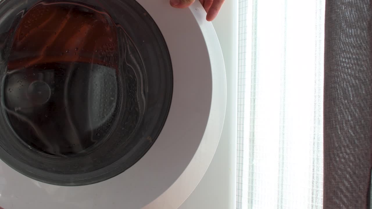 세탁기 문 을 열고 있는 손 의 앞면