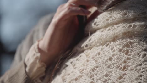 close-up view of gentle hand movement adjusting cozy cashmere shawl in soft winter light outdoors.