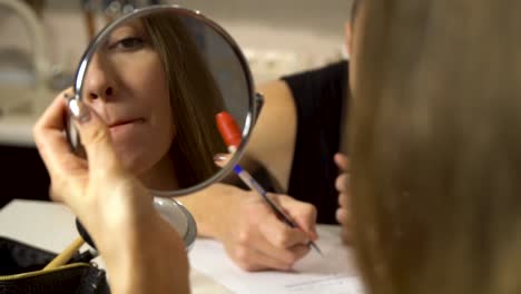 woman applying lipstick in front of a mirror