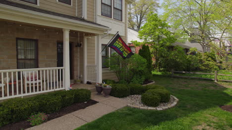 pull back from a nice house in the suburbs with a rainbow flag hanging off the front porch and waving in the breeze