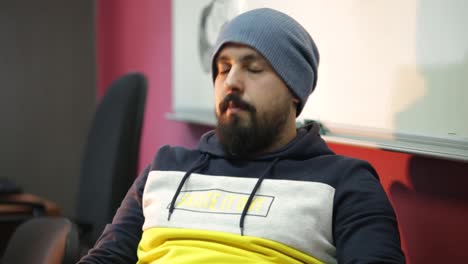 man in a stylish outfit working hard in a modern cozy office, gets tired, massages his nose bridge, lays back to his chair